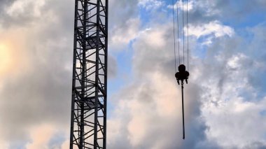 Bir vincin çarpıcı ve dramatik görüntüsü canlı, renkli bir gökyüzüne karşı büyük bir ağır ekipman kaldırıyor.
