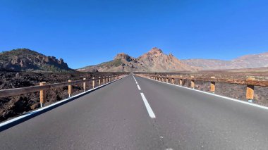 Berrak mavi gökyüzünün altında nefes kesici volkanik araziyi kesen güzel bir yolu gösteren nefes kesici bir manzara