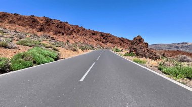 Engebeli bir araziye kurulmuş dolambaçlı bir dağ yolunun göz kamaştırıcı manzarasını deneyin.