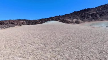 Temiz mavi gökyüzünün altında eşsiz tepe oluşumlarıyla çorak bir çöl manzarası..