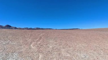 İnanılmaz genişlikte bir çöl manzarasının nefes kesici ve büyüleyici görüntüsü canlı mavi bir gökyüzünün altında uzanıyor.