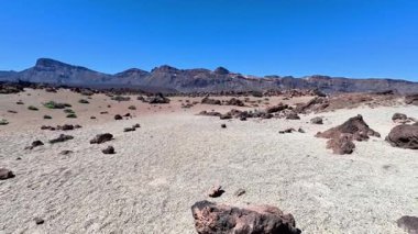 Engin bir çöl sahnesinde doğal güzellikleri yansıtan güzel ve berrak bir gökyüzü altında çarpıcı kayalık oluşumlar görülür.