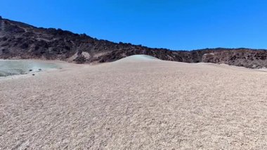 Geniş ve kurak bir manzara, eşsiz jeolojik özellikler sergiliyor, hepsi berrak ve güzel mavi bir gökyüzü altında.