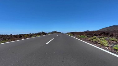 Berrak mavi gökyüzünün altında nefes kesen volkanik bir arazide güzel ve çarpıcı bir dağ yolu.