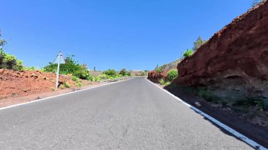 Nefes kesici bir yol yukarıdaki açık mavi gökyüzünün altında hayat dolu canlı bir arazide esiyor.