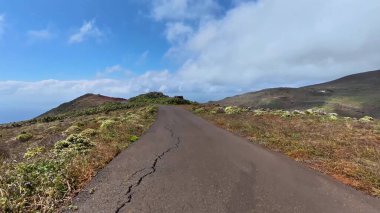 Bereketli bitki örtüsü ve dramatik gökyüzü ile çevrili dolambaçlı bir yol boyunca bir yolculuğa çıkın.