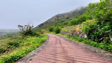 Bereketli tepelerin arasından dolambaçlı bir yol, sisle kaplanmış, doğa severler ve açık hava meraklıları için ideal.