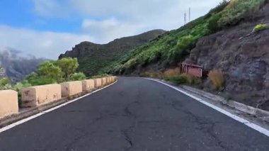 Nefes kesen manzara, verimli yeşillikler ve yüksek uçurumlarla çevrili dolambaçlı bir dağ yolunu gösteriyor.