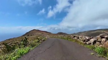 Etrafı yemyeşil ve mavi gökyüzüyle çevrili pitoresk bir dağ yolu. Seyahat için mükemmel.