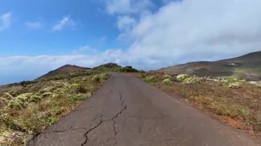 Bereketli bitki örtüsü ve dramatik gökyüzü ile çevrili dolambaçlı bir yol boyunca bir yolculuğa çıkın.