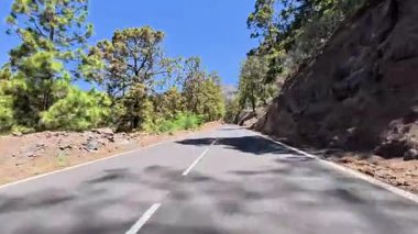 Bereketli yeşillik ve kayalık arazide gezinen dolambaçlı bir yolun nefes kesici ve resimsel manzarasını tecrübe edin.