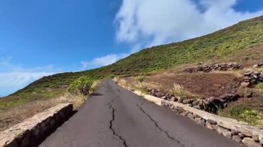 Etrafı canlı yeşilliklerle ve kabarık bulutlarla çevrili dolambaçlı bir yolun çarpıcı manzarası, keşifleri davet ediyor.