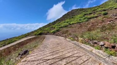 Güzel, dolambaçlı bir yol, açık mavi bir gökyüzünün altında, renkli bir yamaç boyunca kıvrılır. Doğa aşıkları için mükemmel.