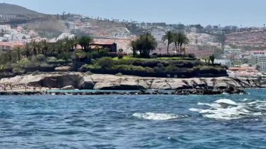 Çarpıcı ve pitoresk bir manzara. Palmiye ağaçlarıyla süslenmiş bir kıyı adasını sergiliyor. Şehir zeminine karşı kurulmuş.