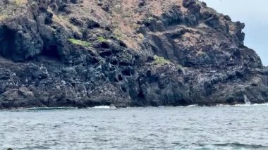 Güçlü okyanus dalgaları altında çarpışan kayalık oluşumları içeren büyüleyici bir sahne.