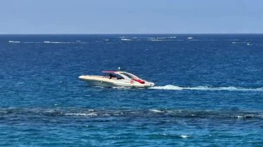 Parlak güneşli bir günde parlak ve ışıltılı okyanus sularında zarif ve hızlı bir tekne süzülüyor.