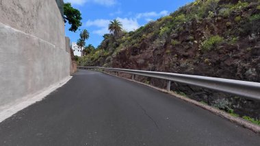 Bereketli yeşillik ve kayalık oluşumlarla çevrili güzel bir kıyı yolunun çarpıcı ve resimsel manzarası.