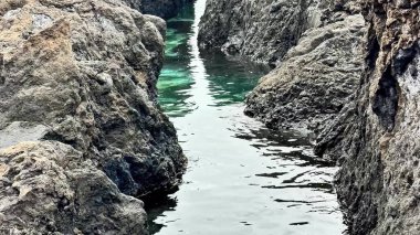 Açık yeşilimsi suların bulunduğu kayalık bir deniz manzarası keşfi ve keşfi çağrıştırıyor.