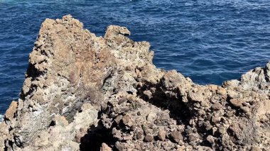 Dalgalı mavi okyanusla çelişen engebeli kayaların nefes kesici manzarası, sahil manzarası hayranları için mükemmel.