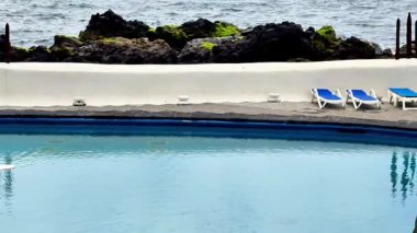 Huzurlu bir deniz havuzu, çarpıcı okyanus manzarası ve rahatlamak için rahat şezlonglar.