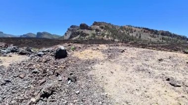 Parlak mavi gökyüzünün altındaki dağınık yeşilliklerle bezenmiş muhteşem kayalık araziyi keşfetmek için bir yolculuğa çıkın.