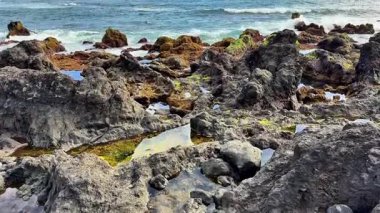 Çarpıcı kayalık kıyı şeridi büyüleyici gel-git havuzlarına ve açık mavi gökyüzünün altında dalgalara sahiptir.