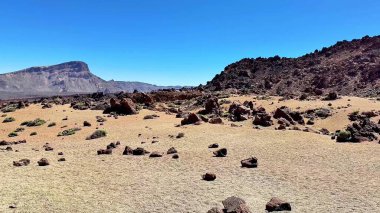 Uçsuz bucaksız, kayalık oluşumlar ve açık mavi gökyüzü ile dolu geniş, engin bir çöle nefes kesici ve çarpıcı bir manzara.