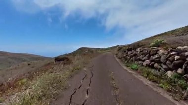 Güzel, güneşli mavi gökyüzünün altında canlı çiçeklerin yetiştiği sakin bir dağ yolunu keşfedin ve keşfedin.