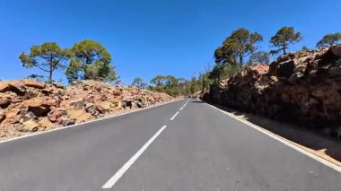 Bu nefes kesici dağ yolunu keşfedin ve keşfedin, canlı ağaçlar ve engebeli kaya oluşumları tarafından güzelce çevrelenmiş.