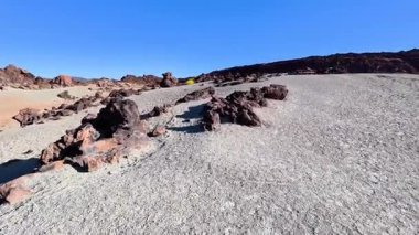 Sersemletici bir kayalık arazi manzarası, eşsiz jeolojik oluşumlara sahip açık mavi gökyüzü ile tezat oluşturuyor.