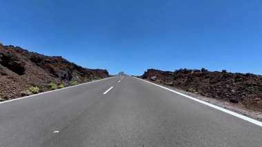 Nefes kesici ve çarpıcı bir yol manzarası üzerinde canlı mavi gökyüzü olan inanılmaz volkanik arazide geziniyor.