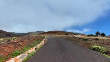 Resimli, dolambaçlı bir yol, açık mavi gökyüzünün altındaki tepelere götürür, doğa severler ve kaşifler için mükemmeldir.