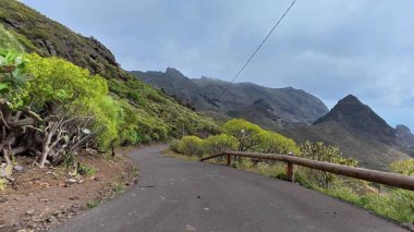 Sersemletici derecede güzel, dolambaçlı bir yol, yemyeşil ve görkemli dağlarla dolu bulutlu bir gökyüzünün altında.