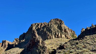 Nefes kesici ve çarpıcı kaya oluşumları, canlı mavi gökyüzüne karşı doğanın ihtişamını gururla sergiliyor.