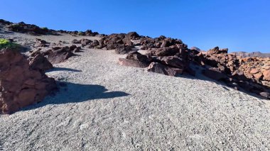 Uçsuz bucaksız bir çöl arazisinde eşsiz kaya oluşumları arasında dolaşan kayalık bir yolun nefes kesici sakin bir görüntüsü.