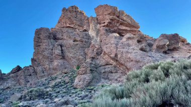 Parlak ve parlak mavi gökyüzünün altında kayalık bir oluşumun büyüleyici ve çarpıcı görüntüsü doğal güzelliği gözler önüne seriyor.