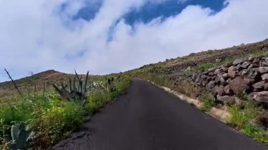 Bereketli yeşilliğin parlak mavi gökyüzüyle buluştuğu dolambaçlı bir dağ yolunun büyüleyici manzarasını deneyimleyin.