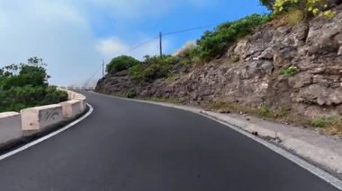 Şaşırtıcı derecede güzel bir yol zarif bir şekilde yükselen uçurumlar boyunca süzülüyor ve berrak mavi gökyüzünün altında yemyeşil bir yer.