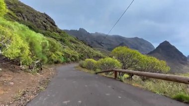 Sersemletici derecede güzel, dolambaçlı bir yol, yemyeşil ve görkemli dağlarla dolu bulutlu bir gökyüzünün altında.