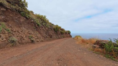 Parıldayan okyanusun üzerindeki dik uçurumlar boyunca uzanan pitoresk toprak yolu keşfedin, nefes kesici manzaralar sunarak