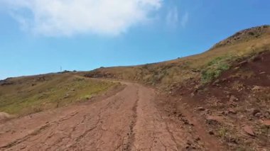 Güzel bir patika, mavi gökyüzünün altındaki görkemli dağlara ve görkemli doğa manzarasına götürür.