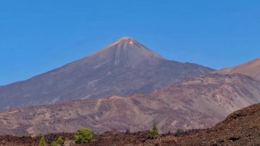 Nefes kesici bir manzara, berrak mavi gökyüzüne karşı kurulmuş bir volkanın ihtişamını ve eşsiz volkanik araziyi yakalar.
