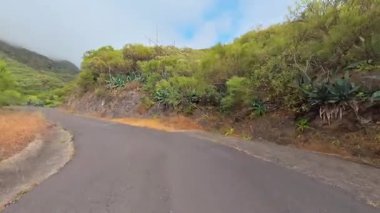 Çevresi canlı yeşilliklerle ve engebeli manzaralarla çevrili güzel, dolambaçlı bir yolun büyüleyici ve çarpıcı manzarası.