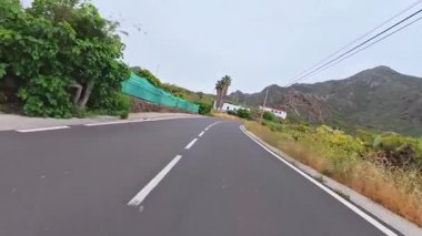 Görkemli dağlar ve yemyeşil sularla çevrili dolambaçlı bir sahil yolunun güzel manzarasının tadını çıkar.