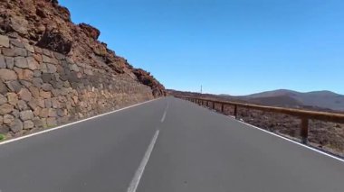 Berrak bir gökyüzünün altında kayalık arazilerle çevrili güzel, dolambaçlı bir yol, seyahat görüntüleri için mükemmel..