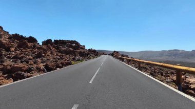 Gökyüzündeki açık mavi gökyüzünün altındaki muhteşem kayalık arazilerin arasından zarif bir şekilde esen pitoresk bir yol.