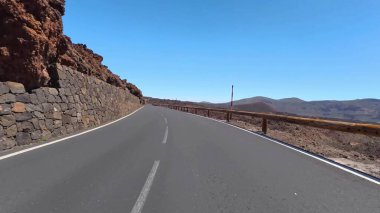 Berrak bir gökyüzünün altında kayalık arazilerle çevrili güzel, dolambaçlı bir yol, seyahat görüntüleri için mükemmel..