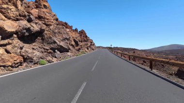 Güzel ve pitoresk bir dağ yolu açık mavi gökyüzünün altındaki kayalık araziyle güzelce çevrilidir.