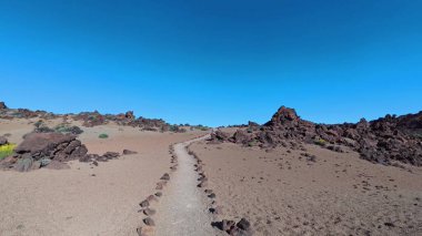 Uçsuz bucaksız bir çöl arazisinde engebeli kayalarla manzaralı bir patika boyunca heyecanlı bir yolculuğa çıkın.
