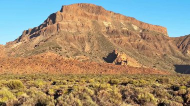 Gün doğumunda sakin bir çöl manzarasına karşı kurulmuş engebeli bir dağın inanılmaz ve nefes kesici manzarası.